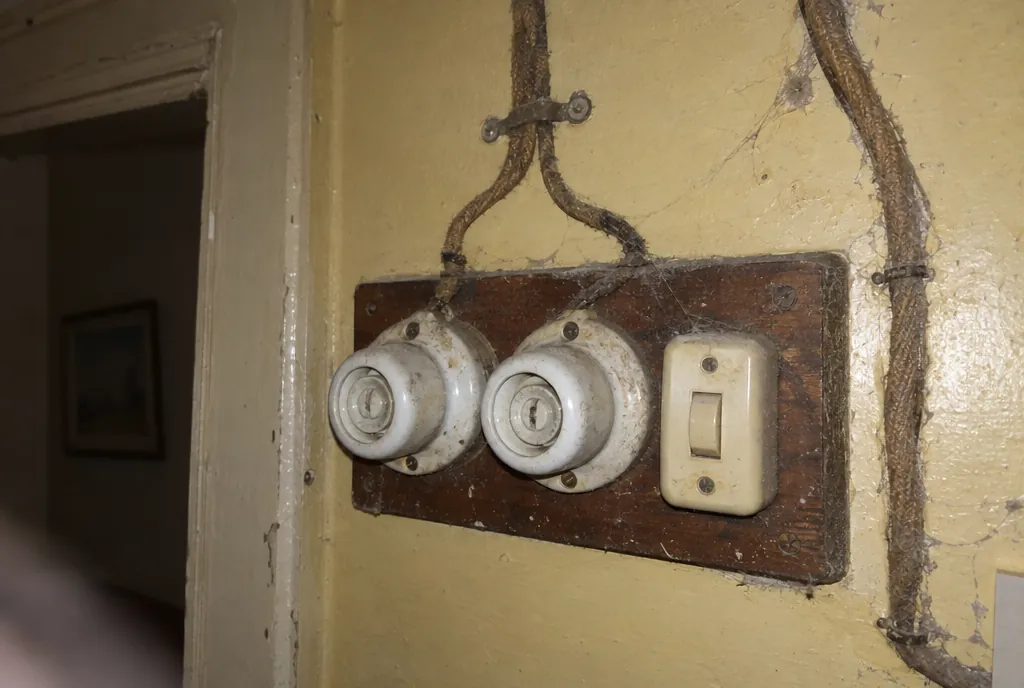 Plomos antiguos de porcelana y un interruptor de baquelita sobre una tabla de madera en un piso antiguo