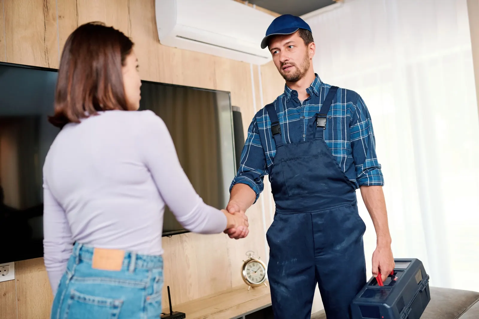 Electricista saludando a una clienta en la puerta de su casa antes de revisar la instalación
