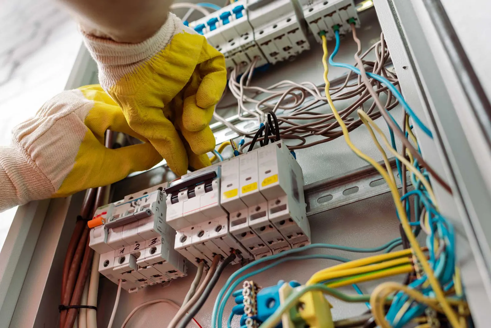 Manos de un electricista señalando los interruptores de un cuadro eléctrico doméstico